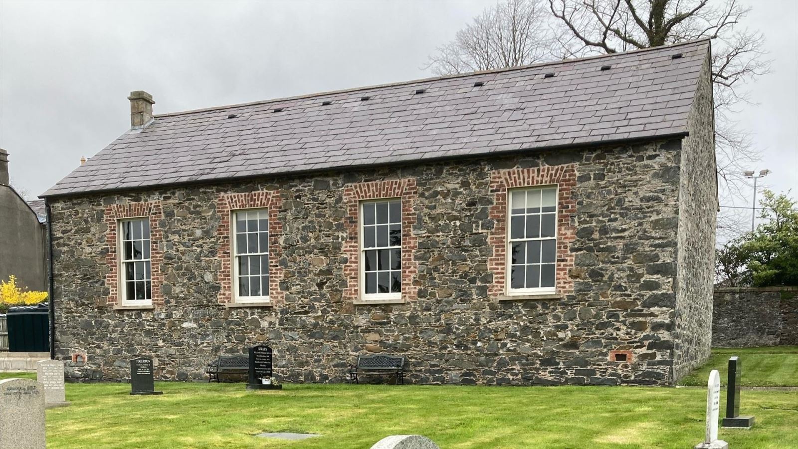 Image of Friends Meeting House, a historical single story building made of grey stone.